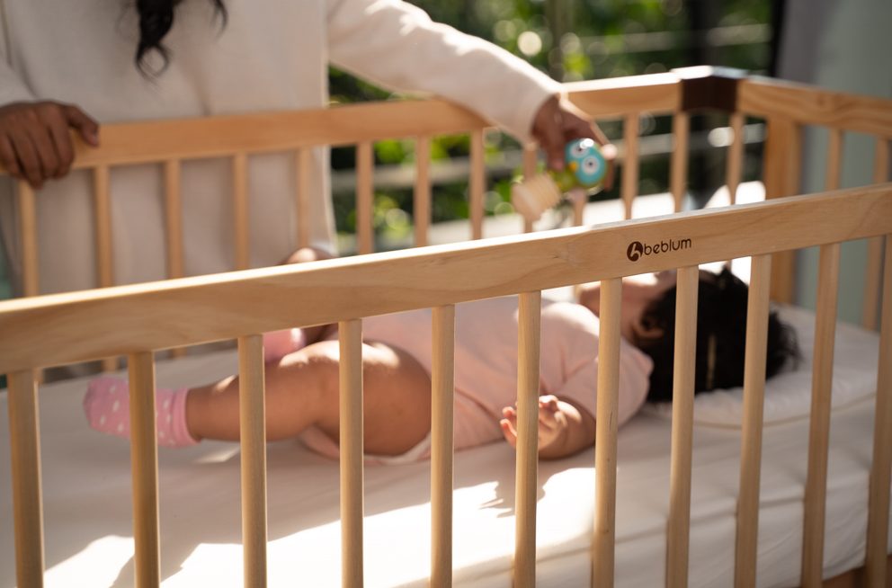 a mother having fun with her baby in the baby cot.
